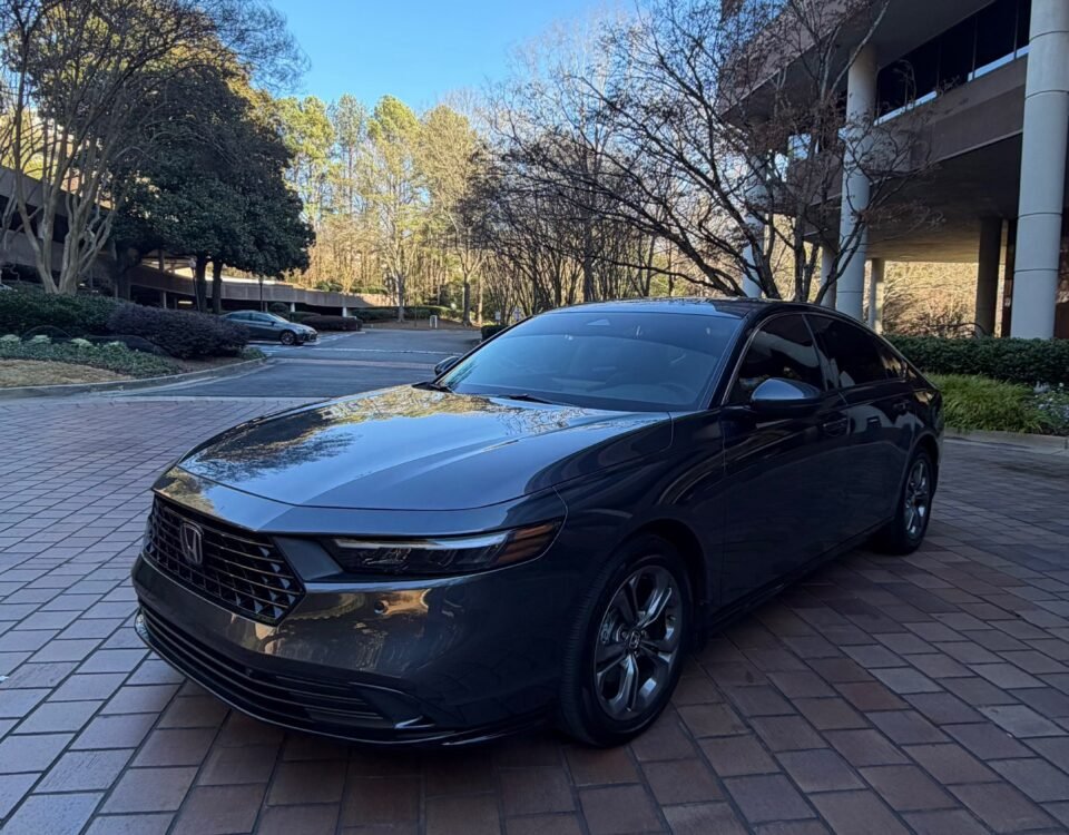snaptik-app-7597857169412869389-slide-3 1 - Dyantransport Black Honda sedan parked on brick driveway in front of a modern glass-front building on a sunny day