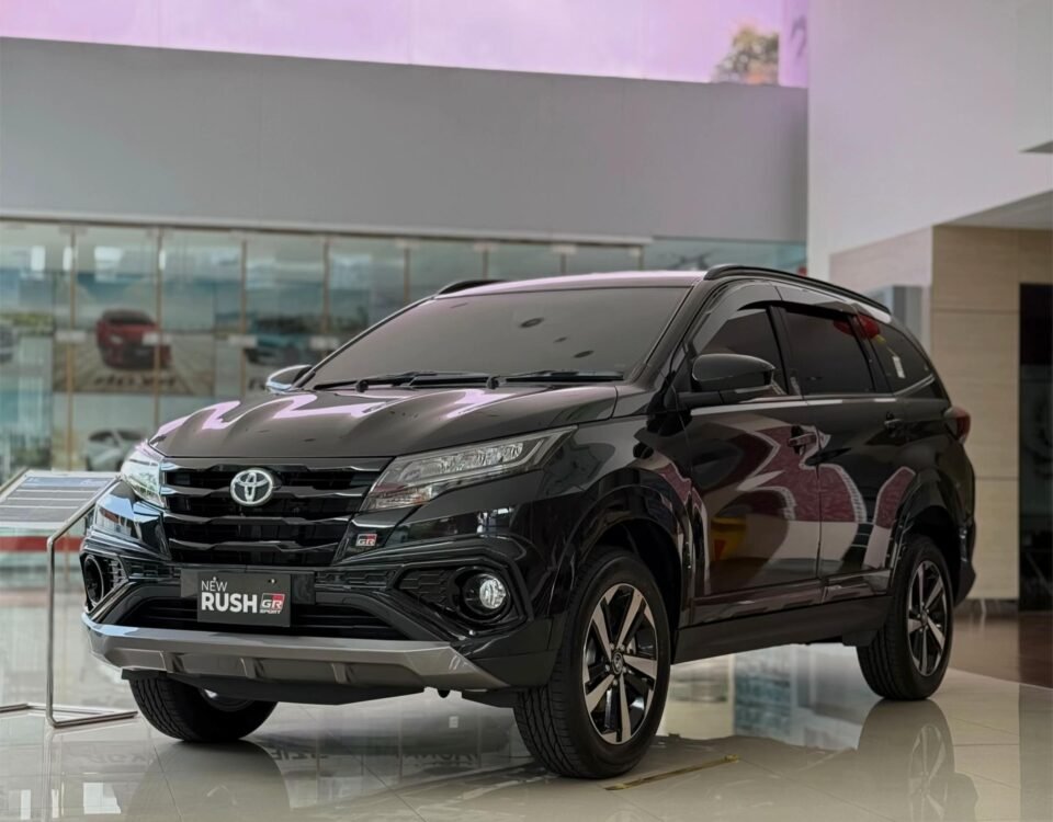 snaptik-app-7608587921343450376-slide-1 - Dyantransport Front three-quarter view of a black Toyota SUV on a bright showroom floor, with the 'New Rush GR' badge on the grille.