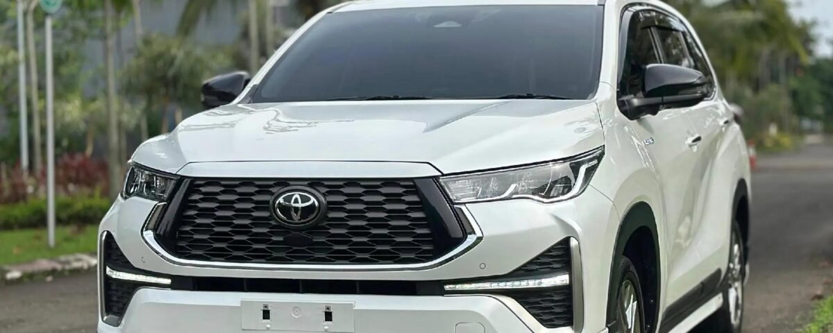 snaptik-app-7613051457994083602-slide-3 - Dyantransport Front view of a white Toyota SUV parked on a road with trees and greenery in the background.