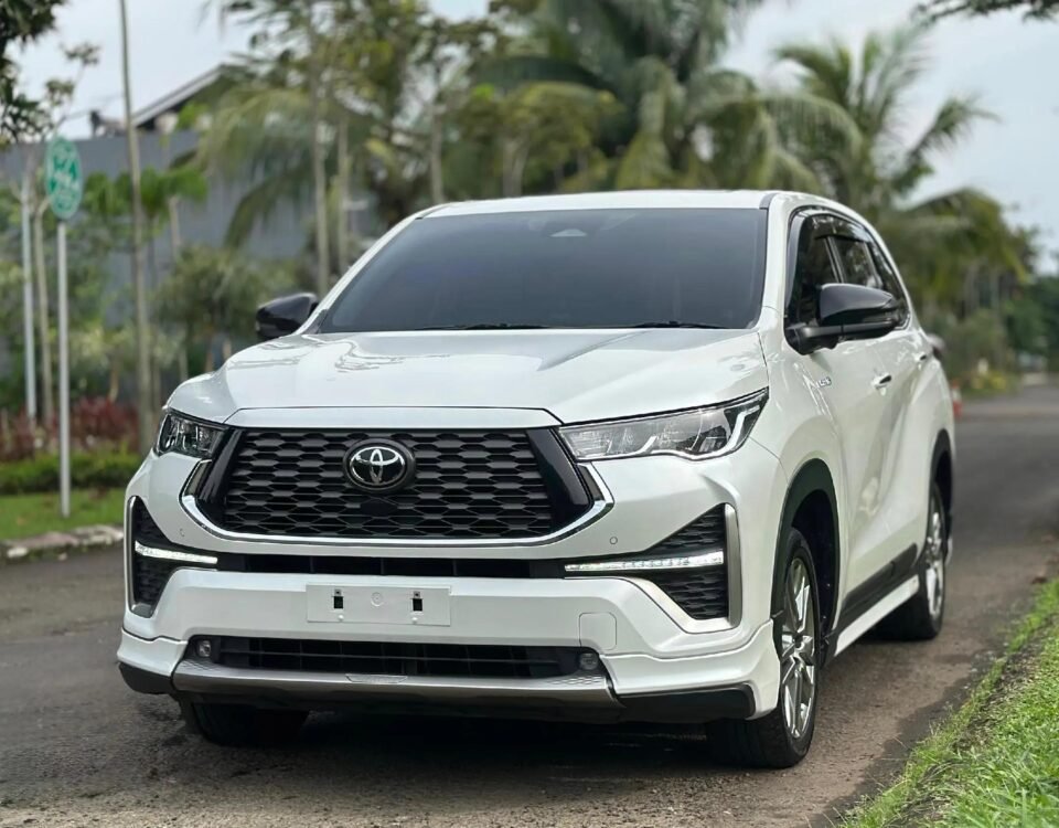 Front view of a white Toyota SUV parked on a road with trees and greenery in the background.