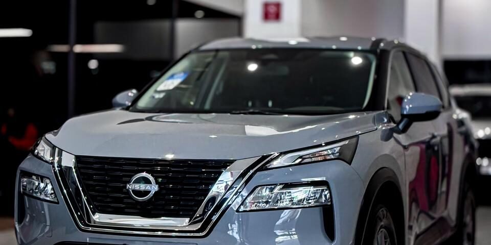 Silver Nissan SUV on display in a bright car showroom with a glossy tiled floor.