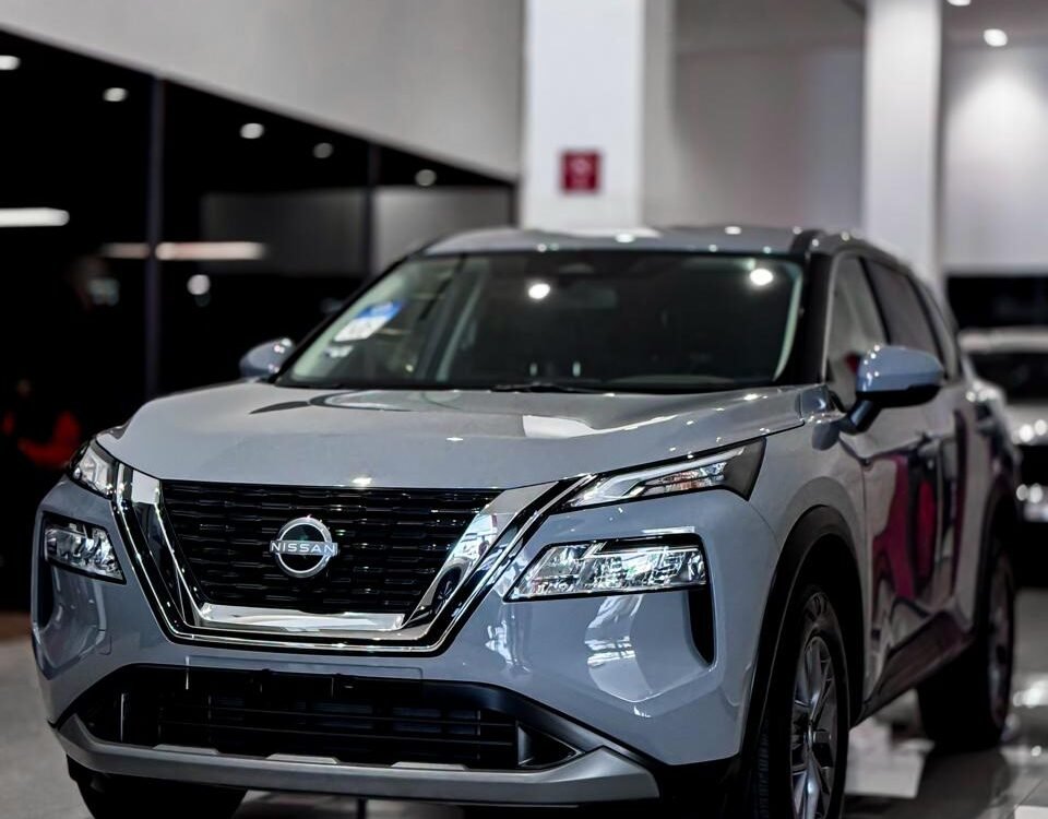 snaptik-app-7620512299085843732-slide-2 - Dyantransport Silver Nissan SUV on display in a bright car showroom with a glossy tiled floor.