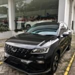 snaptik-app-7635251027083644168-slide-1 - Dyantransport Black SUV parked outside a glass-walled car showroom, front angled toward the camera showing a bold grille and sleek headlights.