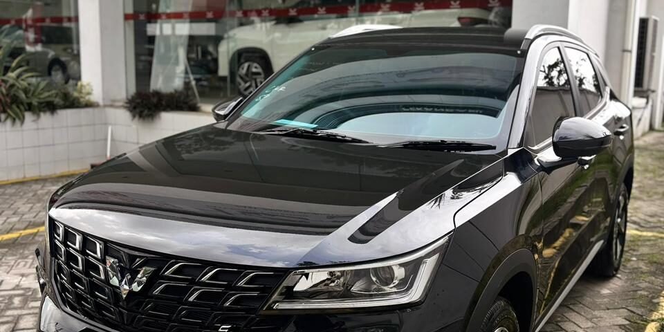 snaptik-app-7635251027083644168-slide-1 - Dyantransport Black SUV parked outside a glass-walled car showroom, front angled toward the camera showing a bold grille and sleek headlights.