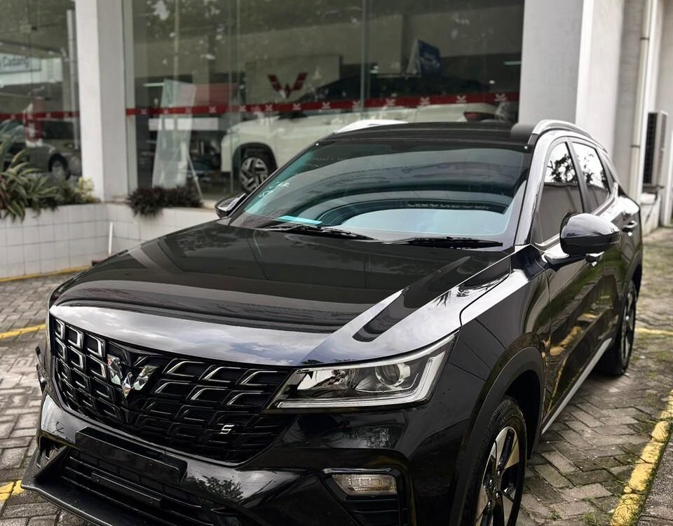 Black SUV parked outside a glass-walled car showroom, front angled toward the camera showing a bold grille and sleek headlights.