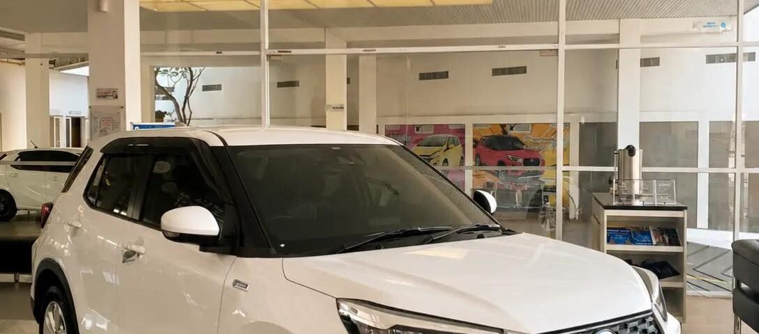 snaptik-app-7644405953135119624-slide-2 - Dyantransport White compact SUV on a showroom floor, facing forward with a bold black grille and 'Rocky' license plate.