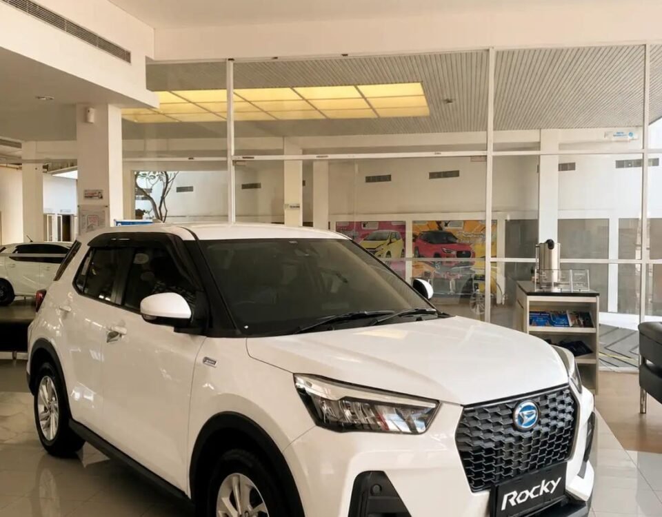 White compact SUV on a showroom floor, facing forward with a bold black grille and 'Rocky' license plate.