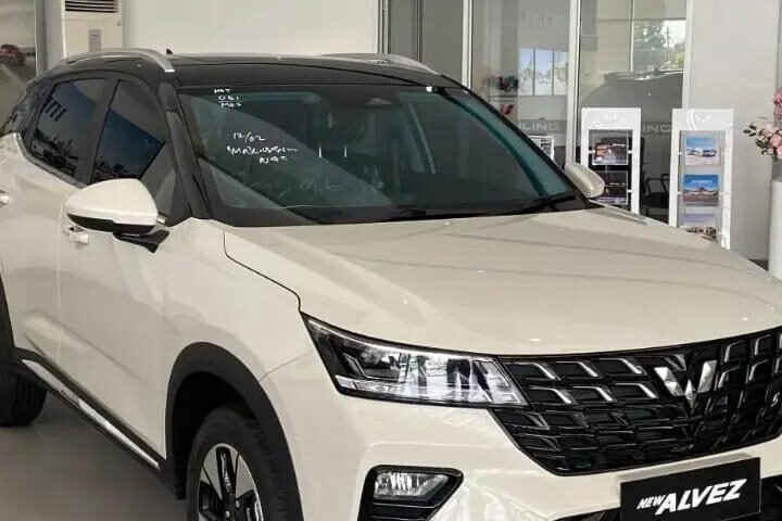White SUV on showroom floor with black grille and modern headlights, labeled NEW AZVEZ (Alvez) on the front plate, bright dealership setting.