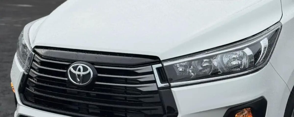 snaptik-app-7659985348444835079-slide-2 - Dyantransport Close-up of a white Toyota SUV front end, showing the grille, emblem, and headlights.