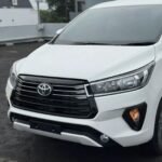 snaptik-app-7659985348444835079-slide-2 - Dyantransport Close-up of a white Toyota SUV front end, showing the grille, emblem, and headlights.