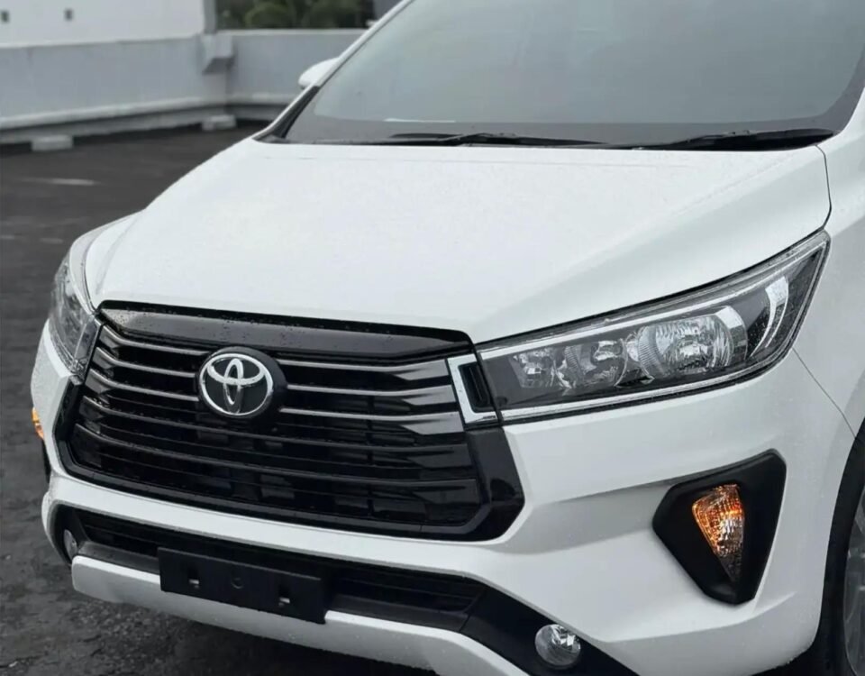 snaptik-app-7659985348444835079-slide-2 - Dyantransport Close-up of a white Toyota SUV front end, showing the grille, emblem, and headlights.