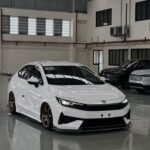 snaptik-app-7663343208537148680-slide-1 - Dyantransport White Honda sedan with bronze aftermarket wheels and lowered suspension in a showroom setting.