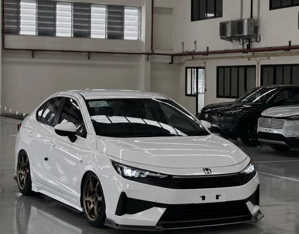 White Honda sedan with bronze aftermarket wheels and lowered suspension in a showroom setting.