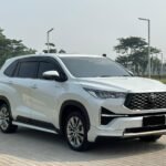 White Toyota SUV parked on a paved area, front three-quarter view showing large grille and sleek headlights.