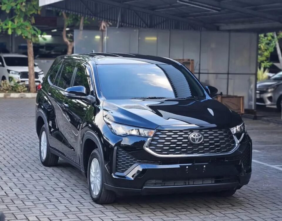 Black Toyota SUV parked on a brick driveway under a metal canopy, reflecting sunlight on its polished surface.